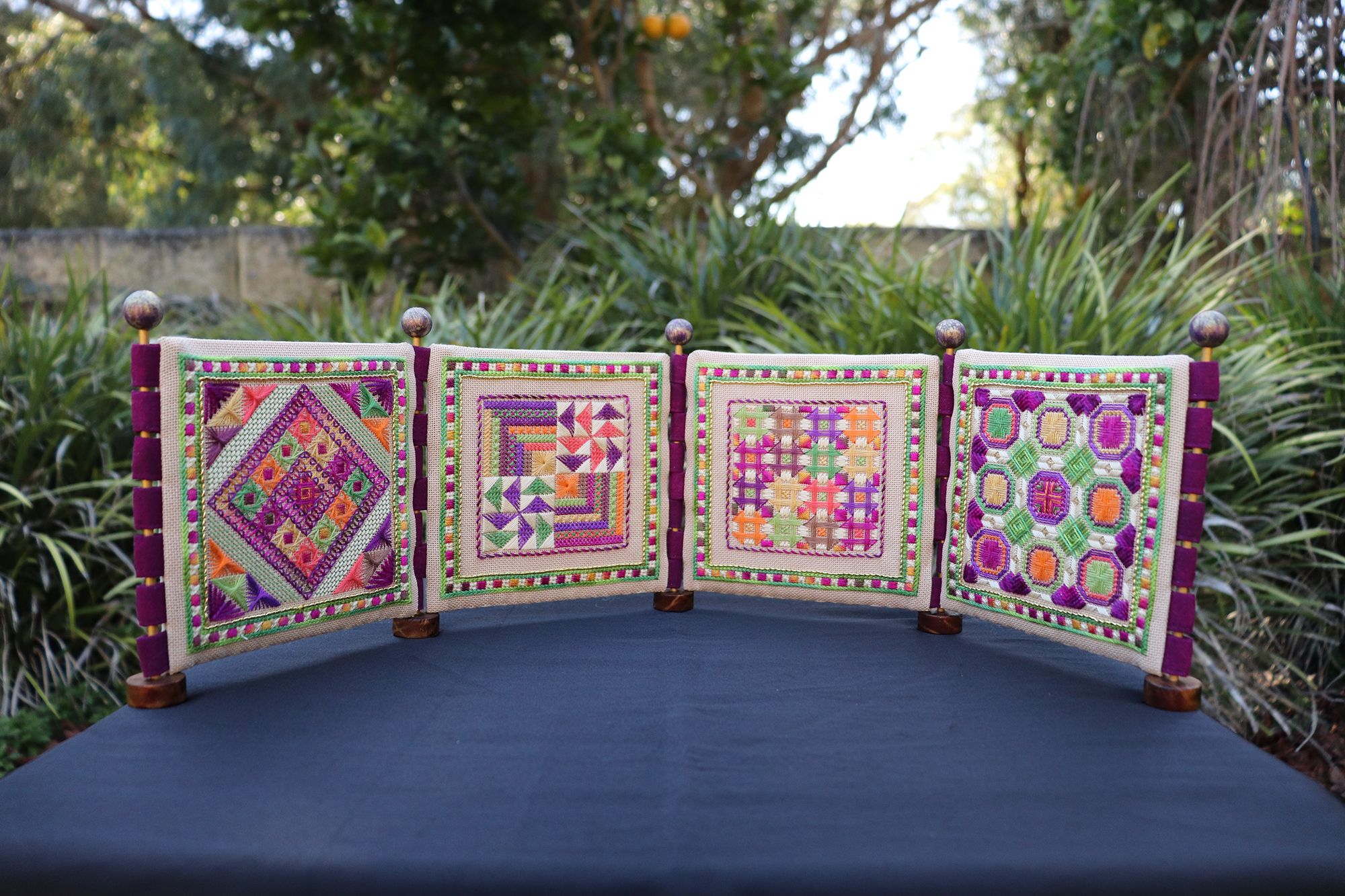 A series of four small, square screens with different embroidery patterns on them.