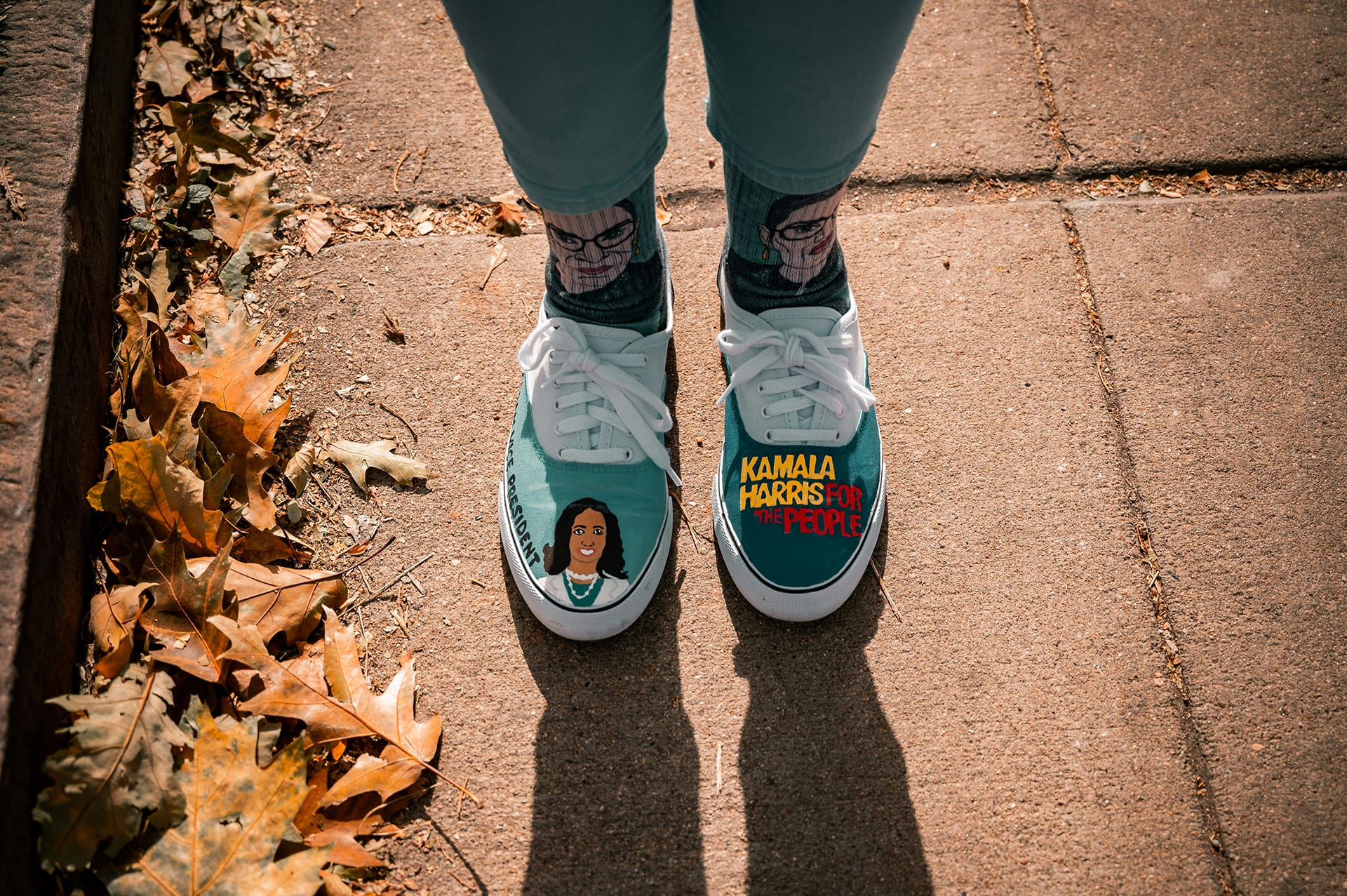 A shot of a person's feet with Kamala Harris painted on their trainers and RGB socks 