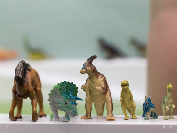 Some toy dinosaurs arranged in a line along the edge of a bath  